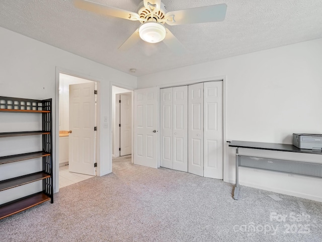 unfurnished bedroom with ceiling fan, light carpet, a textured ceiling, and a closet