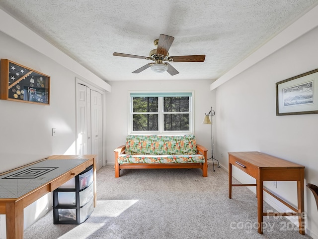 living area with ceiling fan, light carpet, and a textured ceiling