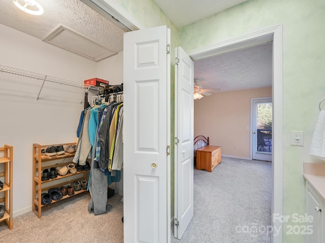 spacious closet with light colored carpet and ceiling fan