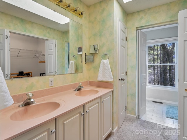 bathroom with tile patterned flooring, vanity, and a skylight