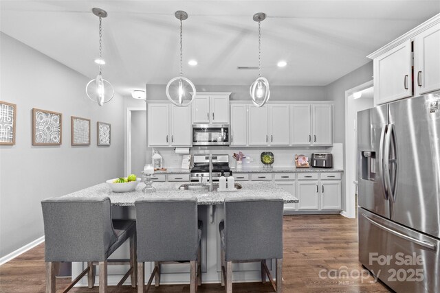 kitchen with appliances with stainless steel finishes, hanging light fixtures, and white cabinets