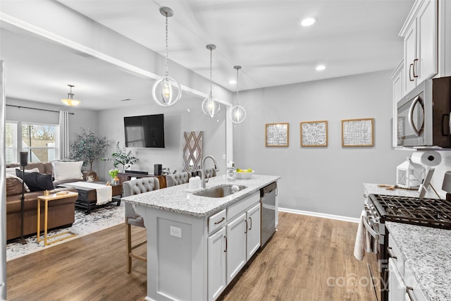 kitchen featuring sink, stainless steel appliances, an island with sink, and white cabinets