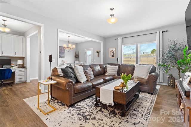 living room featuring a chandelier, built in desk, and light wood-type flooring