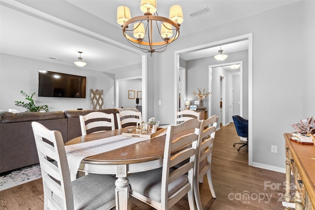 dining area featuring dark wood-type flooring and an inviting chandelier