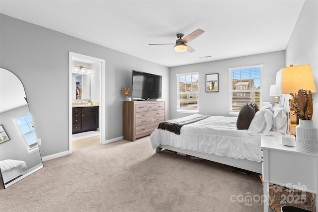 bedroom with connected bathroom, light carpet, and ceiling fan