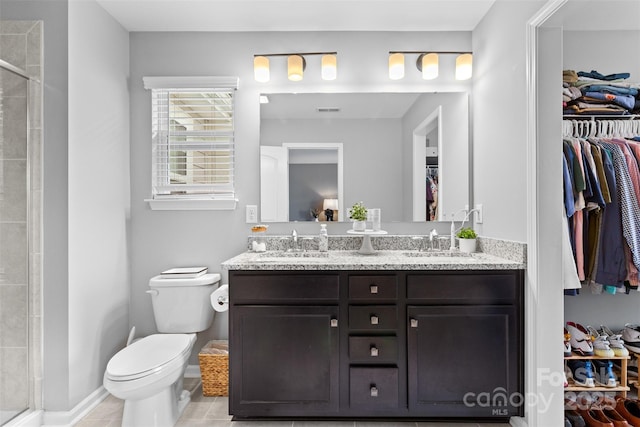 bathroom featuring a shower with door, vanity, tile patterned flooring, and toilet