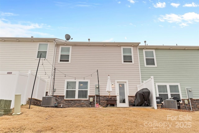 back of house featuring a lawn and central air condition unit