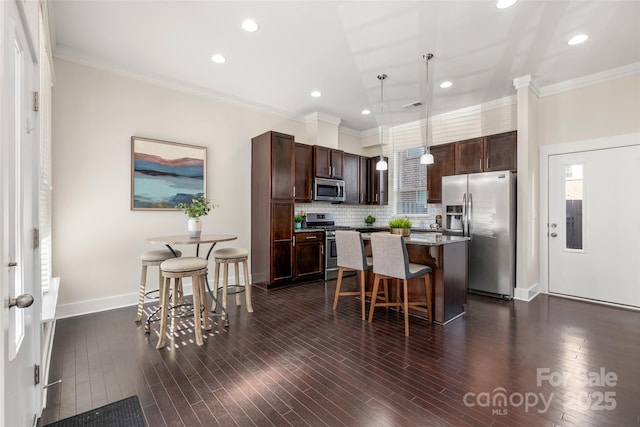 kitchen featuring dark brown cabinetry, hanging light fixtures, a kitchen breakfast bar, a kitchen island, and stainless steel appliances