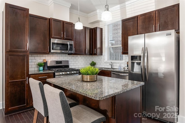 kitchen featuring stone countertops, pendant lighting, a kitchen bar, decorative backsplash, and stainless steel appliances