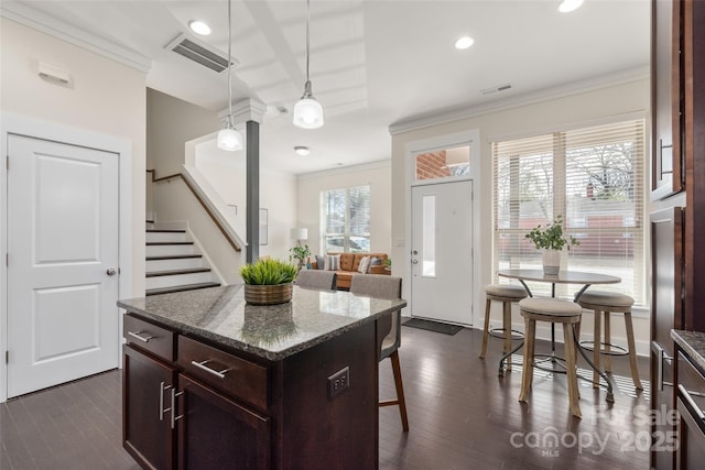 kitchen featuring ornamental molding, a breakfast bar, hanging light fixtures, and a kitchen island