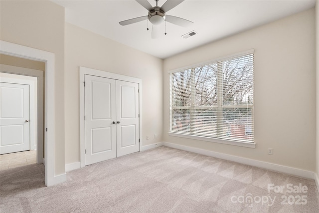 unfurnished bedroom with light colored carpet, a closet, and ceiling fan