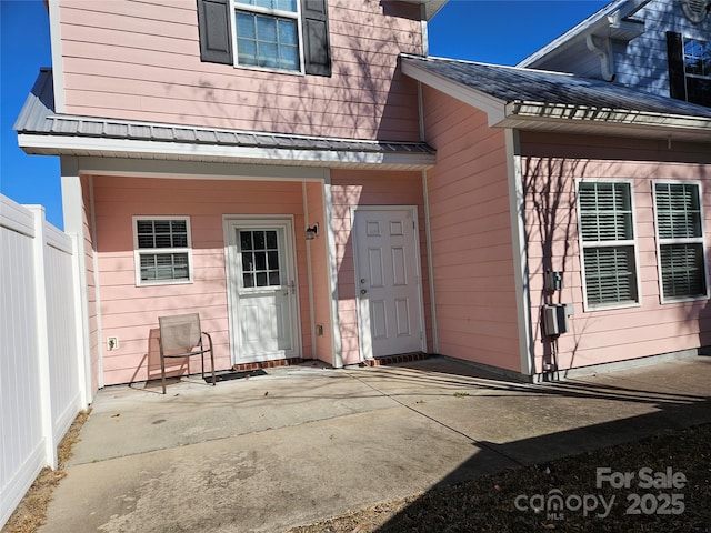 entrance to property featuring fence and a patio