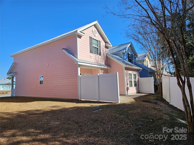 back of house with a standing seam roof, fence, and metal roof