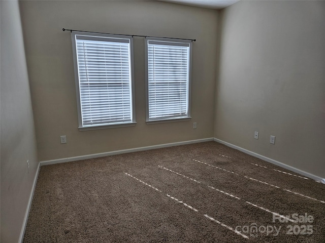 unfurnished room featuring baseboards and dark colored carpet