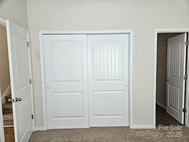 interior space featuring a closet, dark carpet, and baseboards