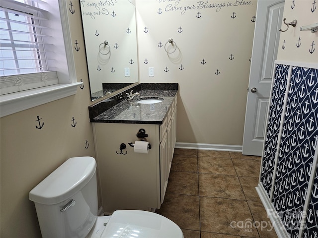 bathroom featuring baseboards, vanity, toilet, and tile patterned floors