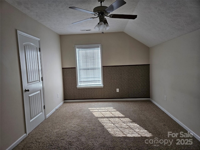 bonus room featuring light carpet, visible vents, a wainscoted wall, vaulted ceiling, and a textured ceiling