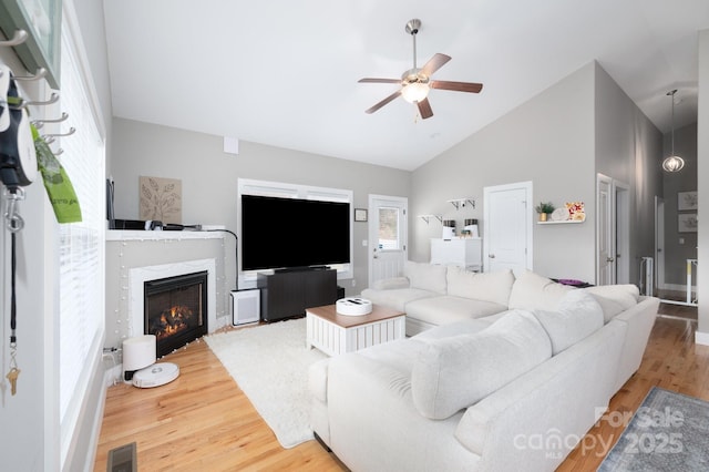 living room with ceiling fan, a high end fireplace, high vaulted ceiling, and hardwood / wood-style floors