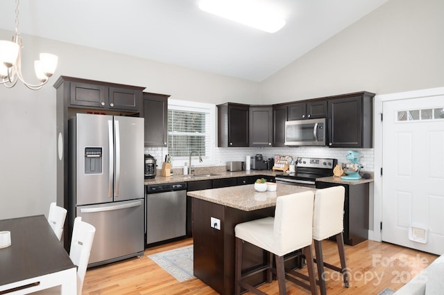 kitchen with sink, decorative light fixtures, a chandelier, appliances with stainless steel finishes, and a kitchen island