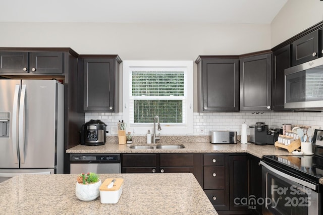 kitchen featuring stainless steel appliances, sink, backsplash, and dark brown cabinetry