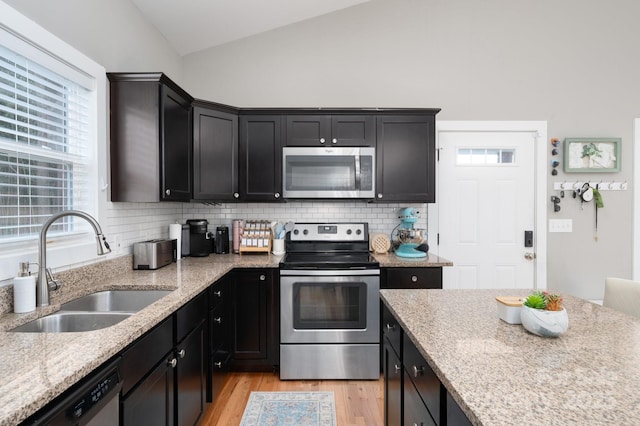 kitchen featuring lofted ceiling, sink, tasteful backsplash, stainless steel appliances, and light hardwood / wood-style floors