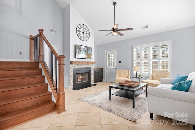 living room with ceiling fan, high vaulted ceiling, light tile patterned floors, and a fireplace