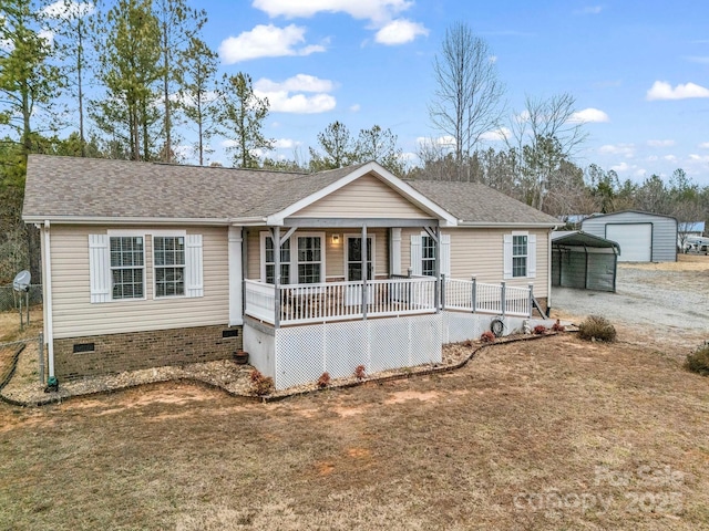 ranch-style home featuring an outbuilding, a front lawn, a carport, and covered porch