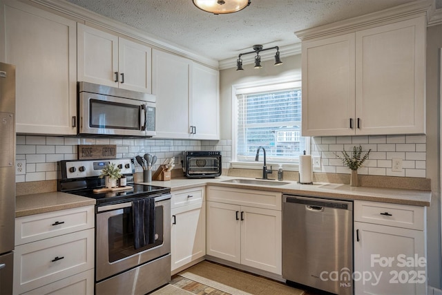 kitchen featuring sink, a textured ceiling, appliances with stainless steel finishes, white cabinets, and backsplash