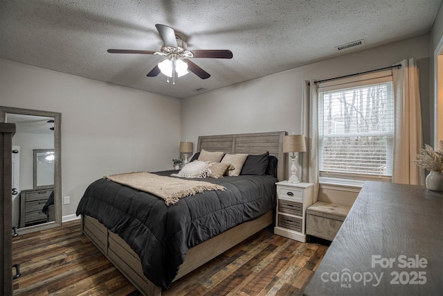 bedroom with ceiling fan, dark wood-type flooring, and a textured ceiling