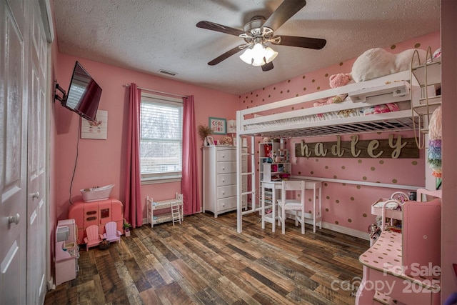 bedroom with dark wood-type flooring, ceiling fan, and a textured ceiling