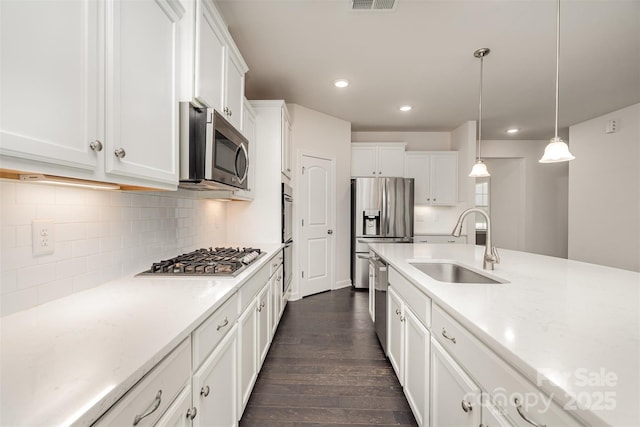 kitchen featuring sink, white cabinetry, decorative light fixtures, appliances with stainless steel finishes, and dark hardwood / wood-style floors