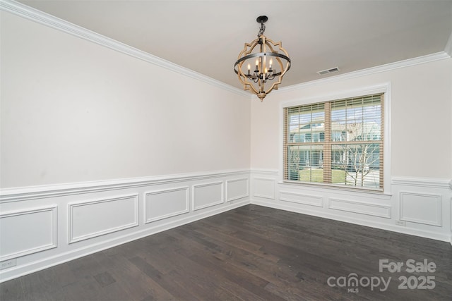 spare room featuring crown molding, dark hardwood / wood-style floors, and a chandelier