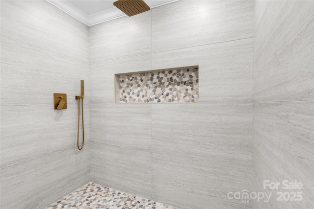 bathroom with crown molding and a tile shower