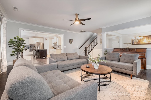 living room with wood-type flooring, ornamental molding, and ceiling fan with notable chandelier