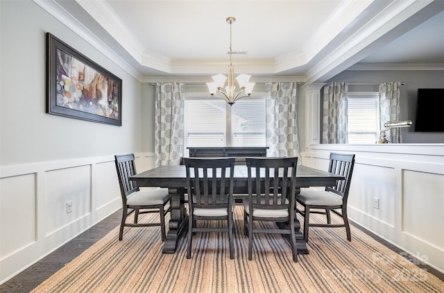 dining room featuring an inviting chandelier, a raised ceiling, crown molding, and hardwood / wood-style floors