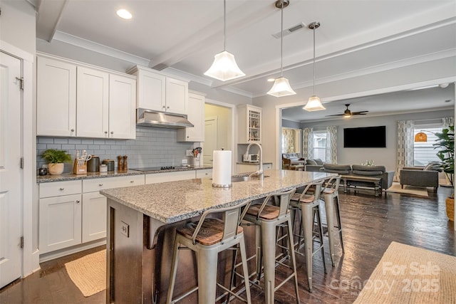 kitchen featuring sink, white cabinets, a center island with sink, and decorative light fixtures