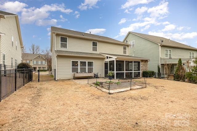 rear view of house featuring a sunroom, a vegetable garden, and a fenced backyard