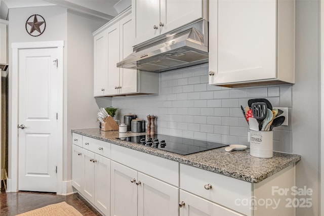 2201 Bluebell Way, Tega Cay, SC 29708 - kitchen with under cabinet range hood, black electric cooktop, tasteful backsplash, white cabinetry, and dark wood-style flooring