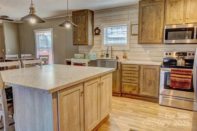 kitchen featuring sink, decorative light fixtures, a center island, a kitchen breakfast bar, and stainless steel appliances