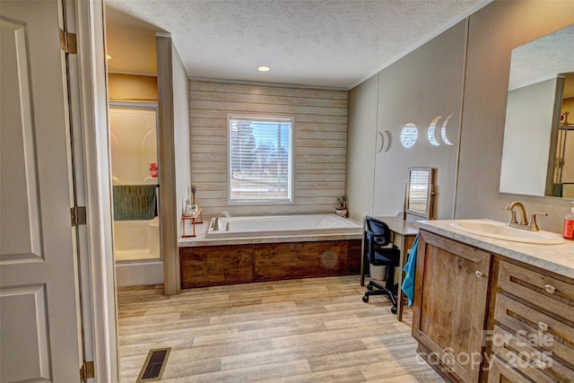 bathroom featuring hardwood / wood-style flooring, vanity, independent shower and bath, and a textured ceiling