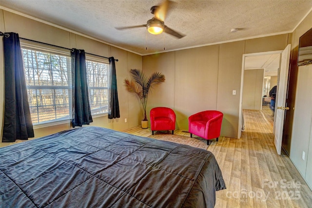 bedroom with ceiling fan, crown molding, a textured ceiling, and light wood-type flooring