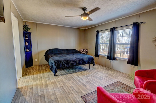 bedroom featuring ceiling fan, ornamental molding, light hardwood / wood-style flooring, and a textured ceiling