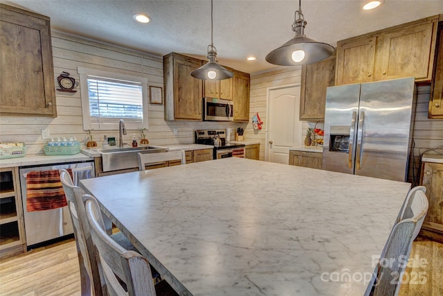 kitchen featuring sink, stainless steel appliances, tasteful backsplash, decorative light fixtures, and light wood-type flooring