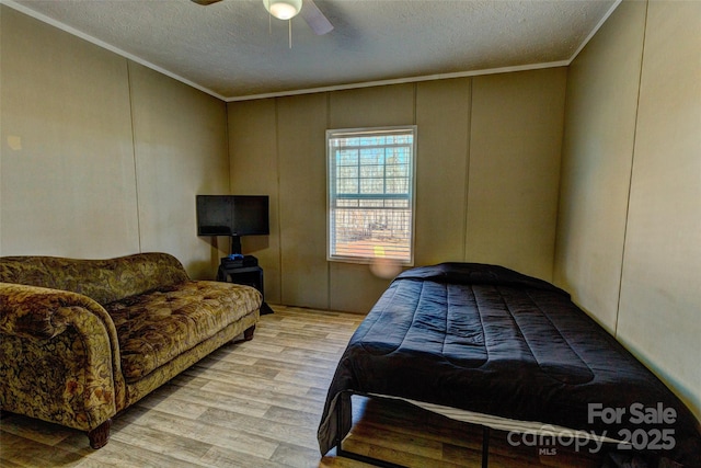 bedroom featuring ceiling fan, crown molding, light hardwood / wood-style floors, and a textured ceiling