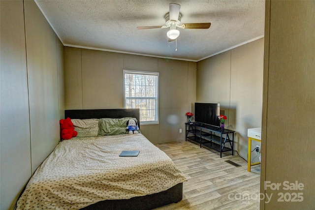 bedroom with ornamental molding, ceiling fan, a textured ceiling, and light hardwood / wood-style floors