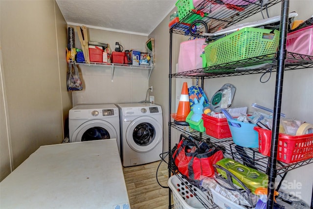 laundry area featuring washer and clothes dryer, a textured ceiling, and light hardwood / wood-style floors