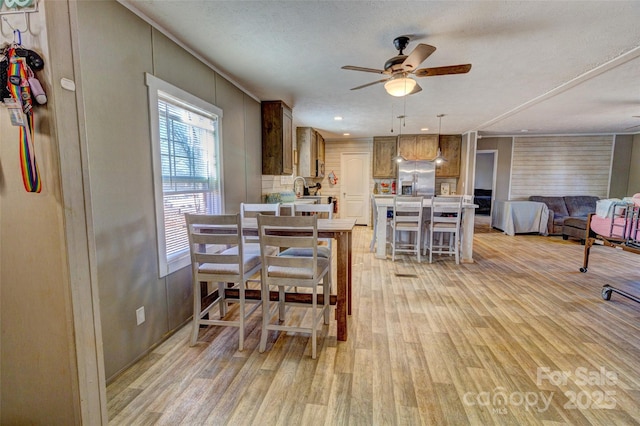 dining room with ceiling fan, light hardwood / wood-style flooring, and a textured ceiling