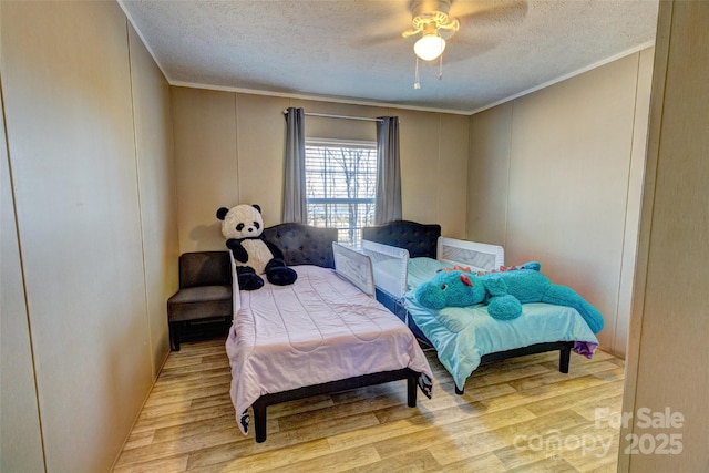 bedroom featuring ceiling fan, crown molding, a textured ceiling, and light wood-type flooring