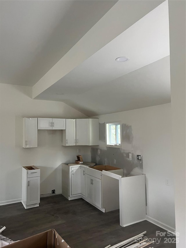 kitchen with vaulted ceiling, dark wood-style flooring, white cabinetry, and baseboards