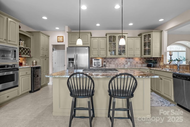 kitchen with stainless steel appliances, a kitchen island, light stone countertops, and beverage cooler